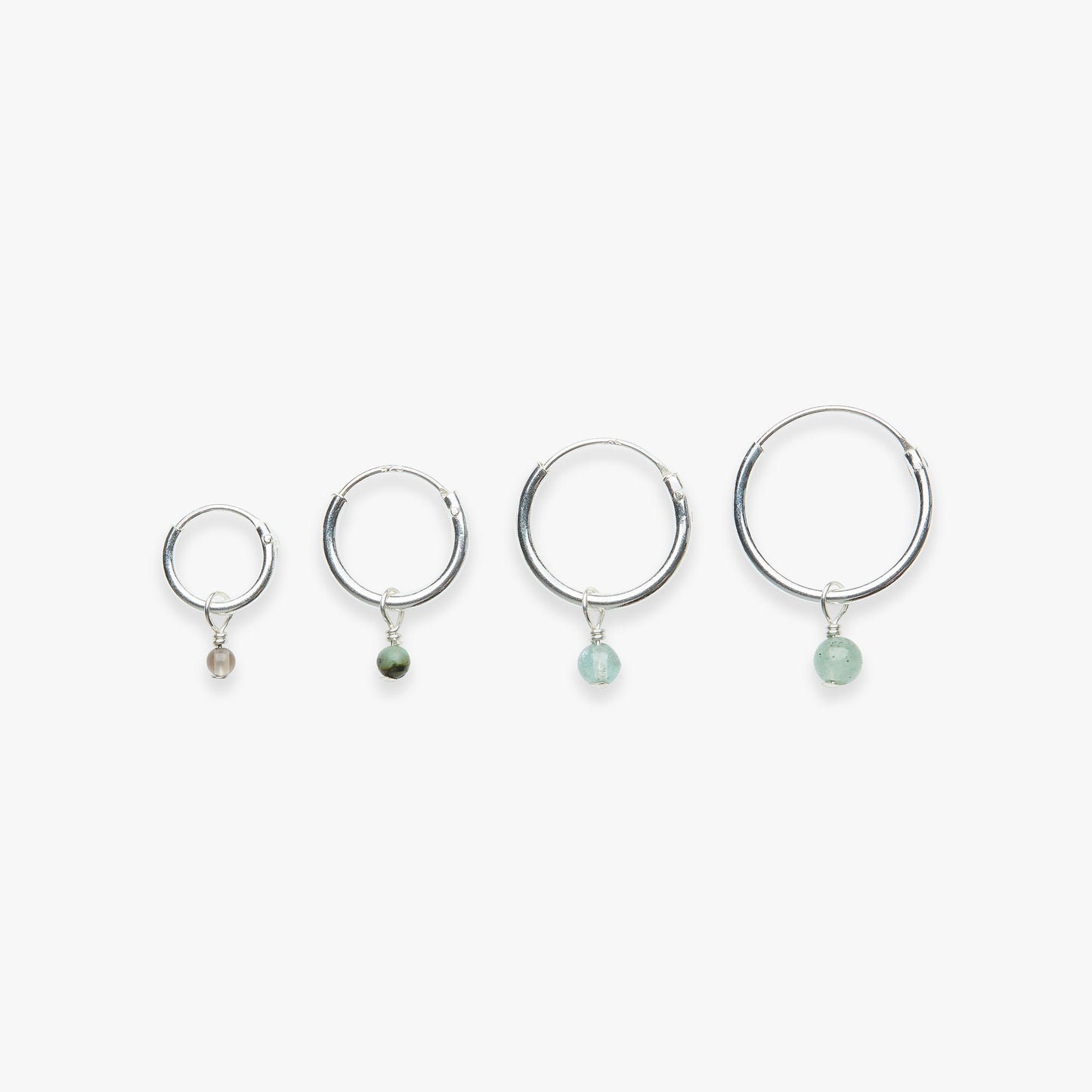 Four silver hoop earrings with gemstone drops on a white background