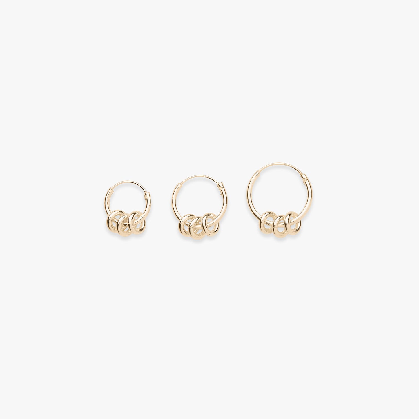 Three gold hoop earrings on a white background