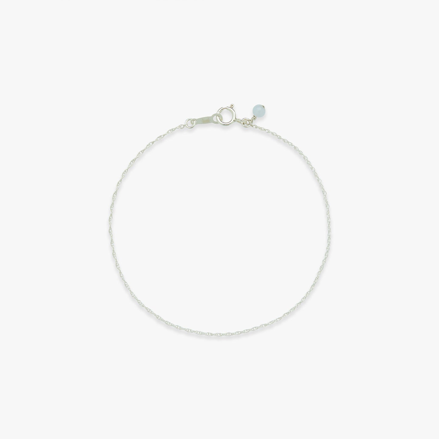 Silver bracelet with a small blue gemstone on a white background