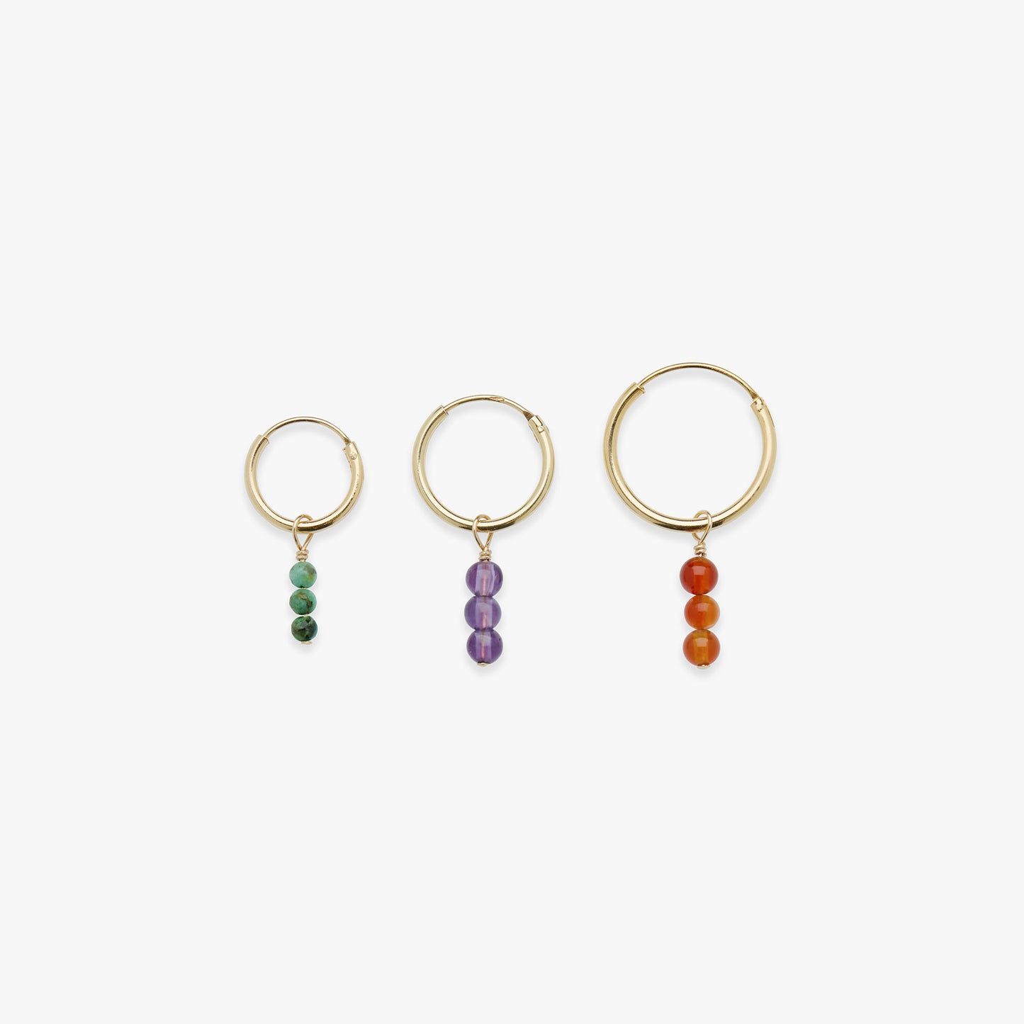 Three gold hoop earrings with bead drops on a white background