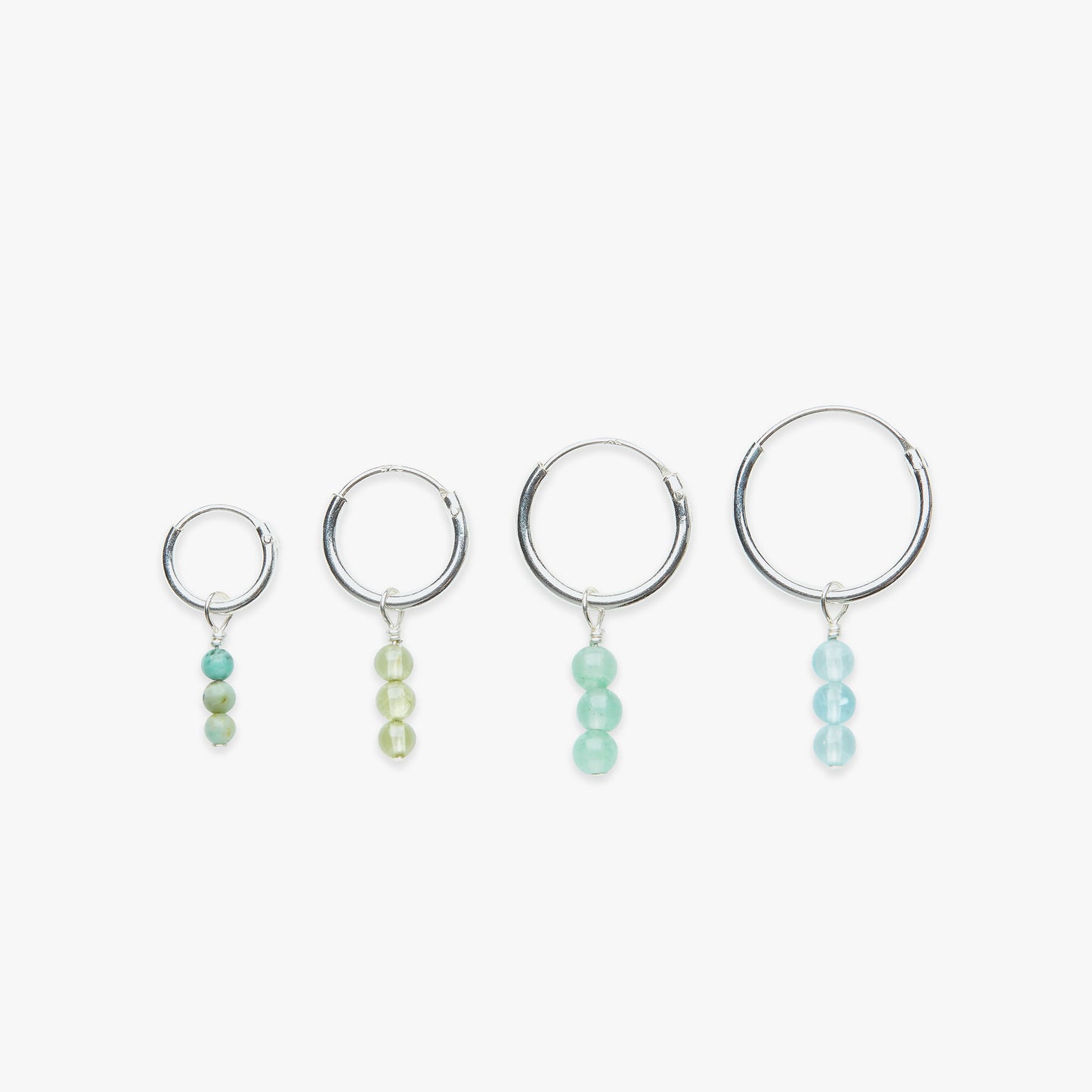 Set of four silver hoop earrings with bead drops on a white background