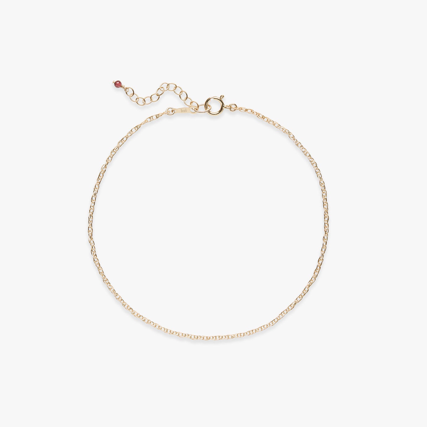 Gold rope chain anklet with a gemstone detail on a white background