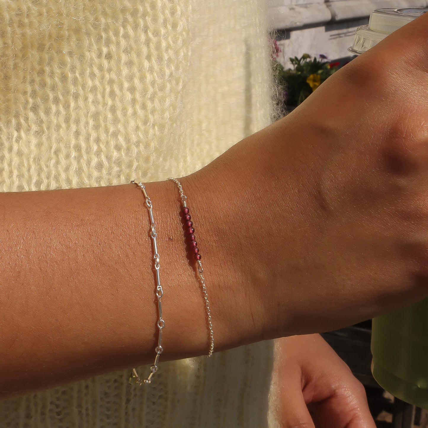 Close-up of a person's wrist wearing two bracelets against a blurred background