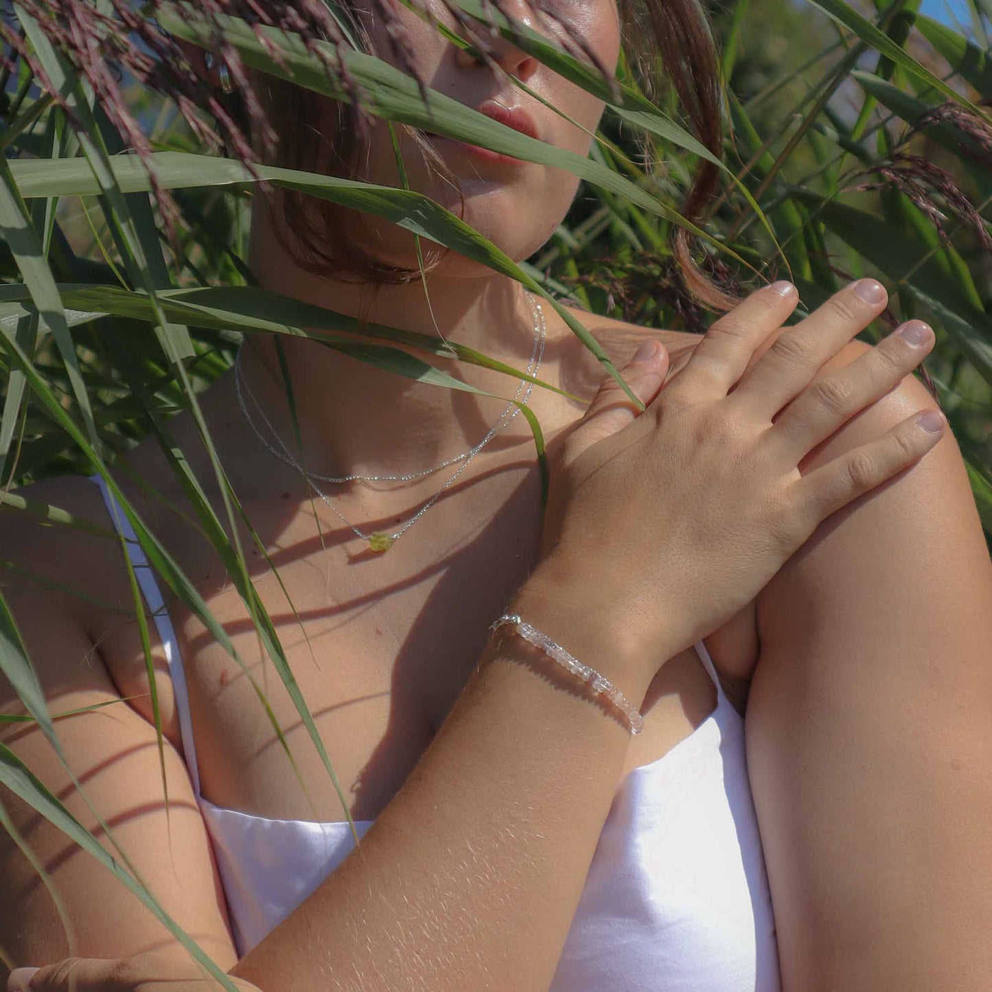 Woman in a white top standing in tall grass with her hands clasped together.
