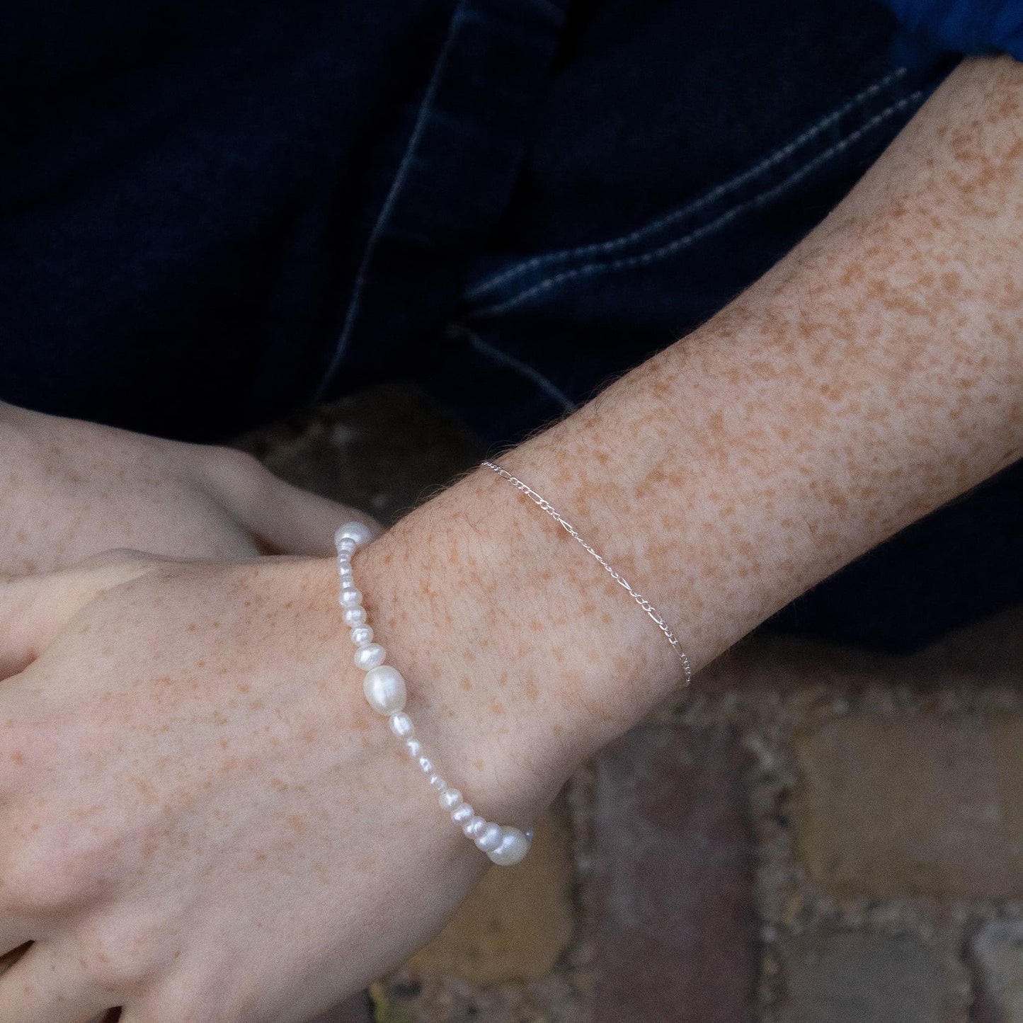 Close-up of a wrist wearing a pearl bracelet with a blurred background