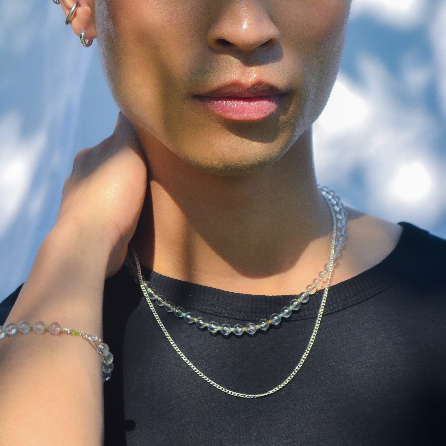 Person wearing a necklace with a blurred natural background