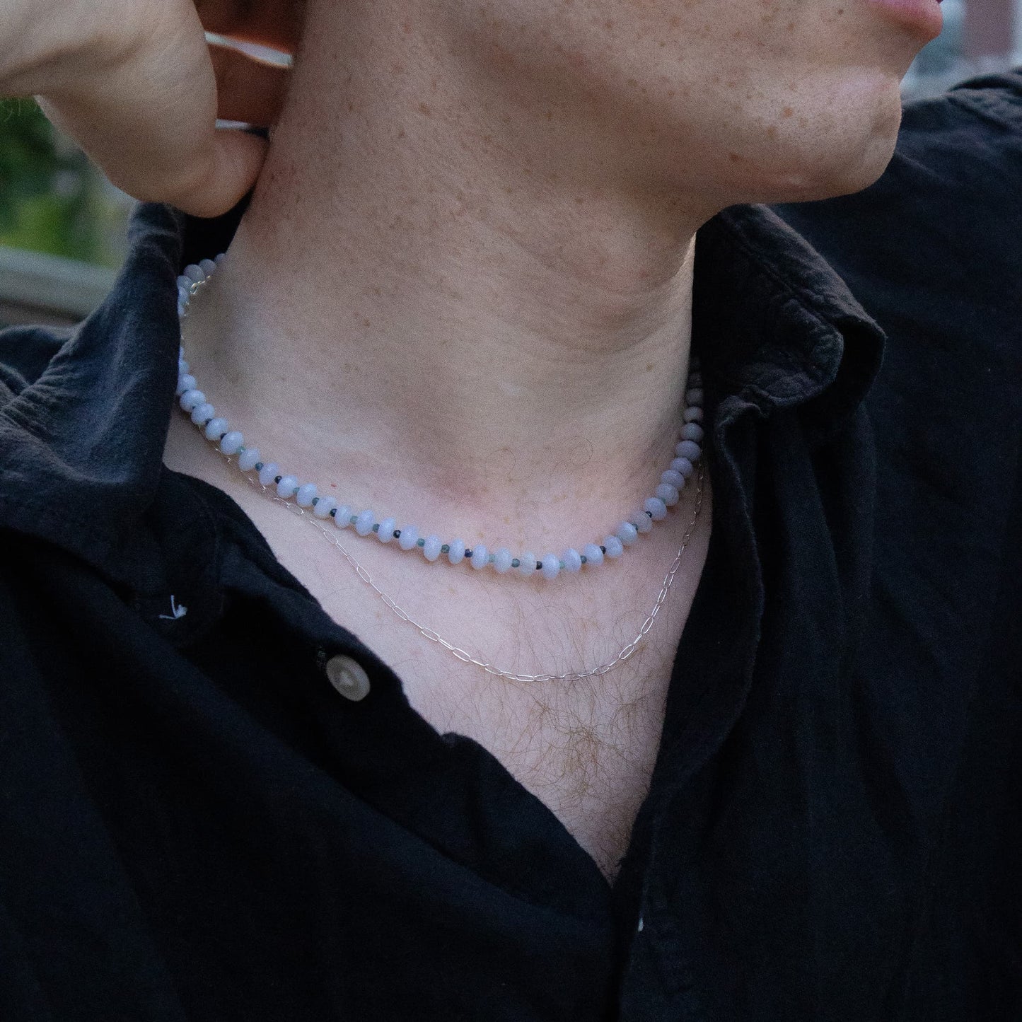 Person wearing a black shirt with a necklace and earrings.