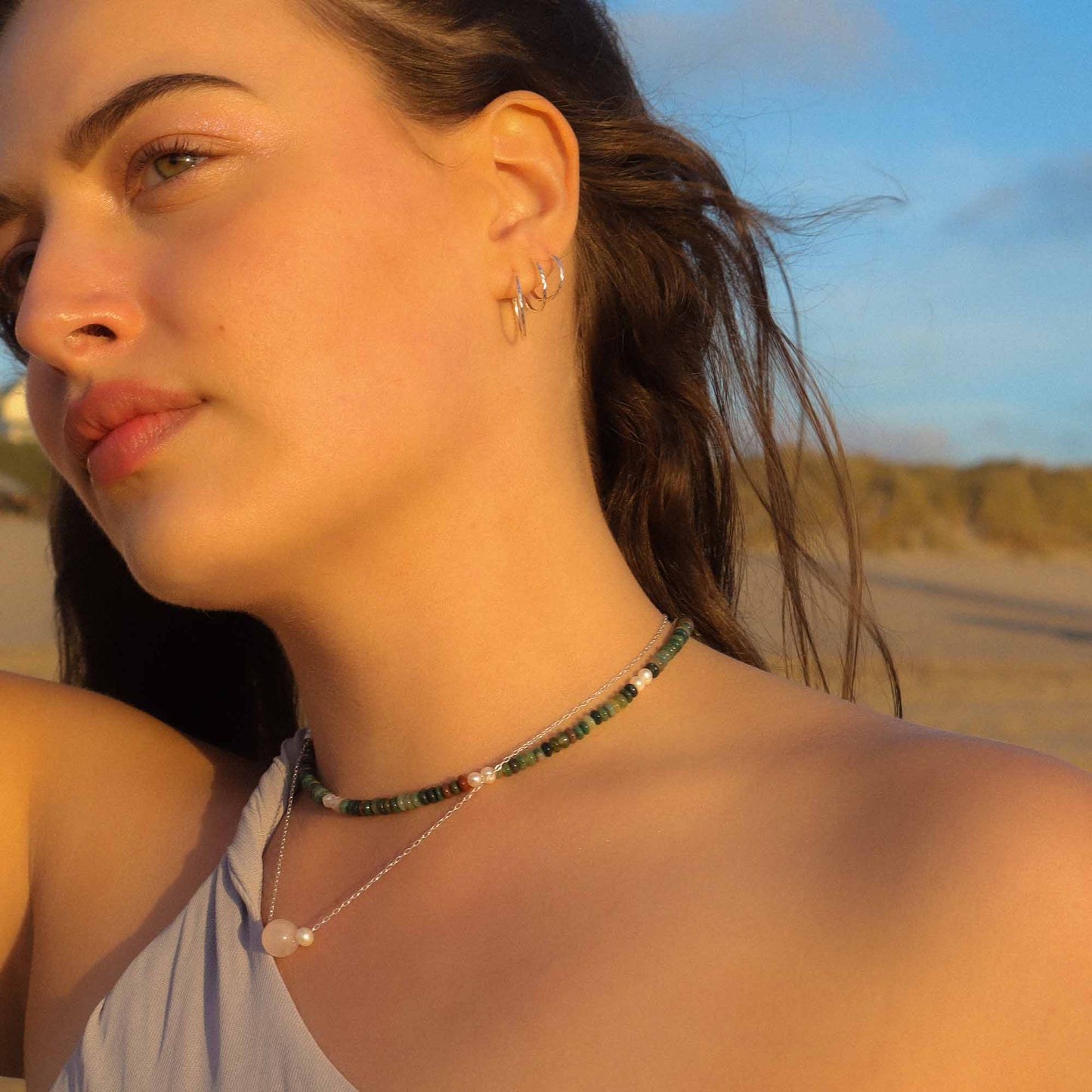 Woman wearing a necklace with a beach in the background