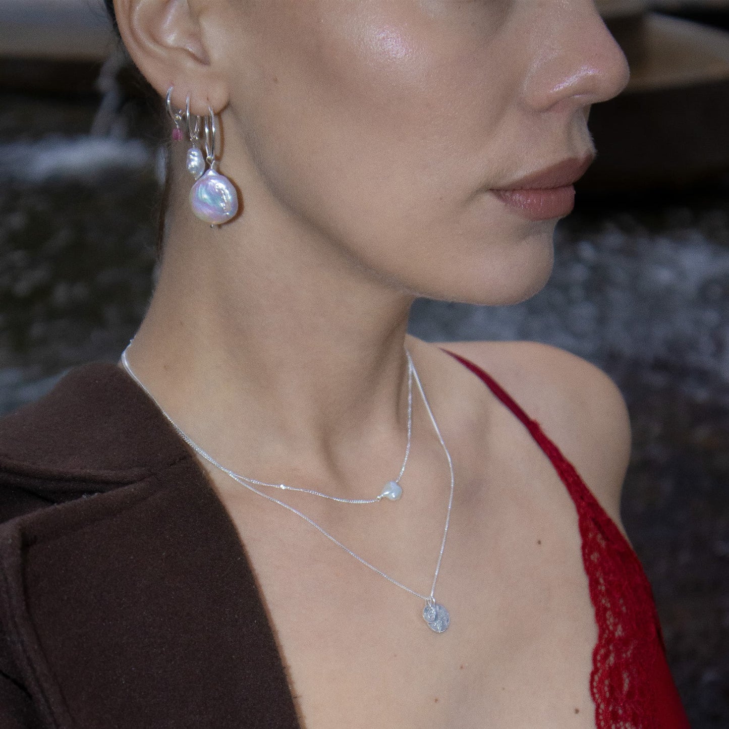 Close-up of a woman wearing earrings and a necklace with a blurred background