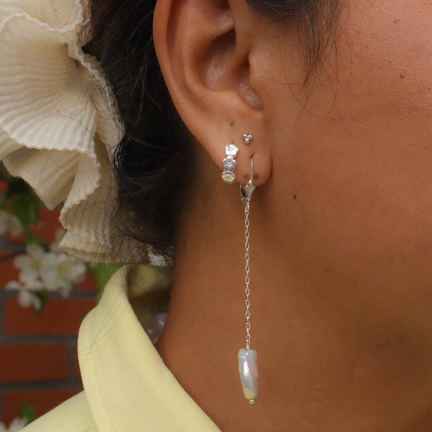 Close-up of an ear wearing a silver earring with a baroque pearl.