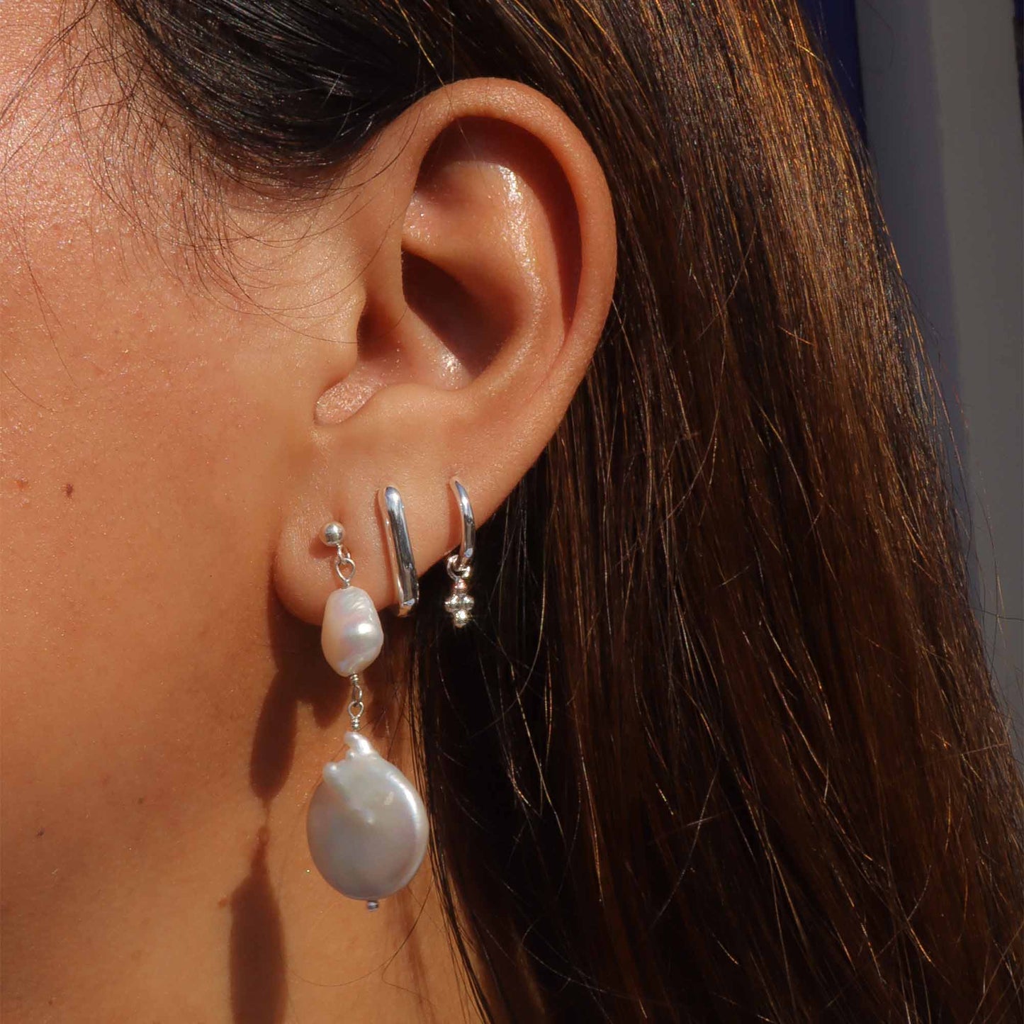 Close-up of an ear wearing pearl earrings with a blurred background