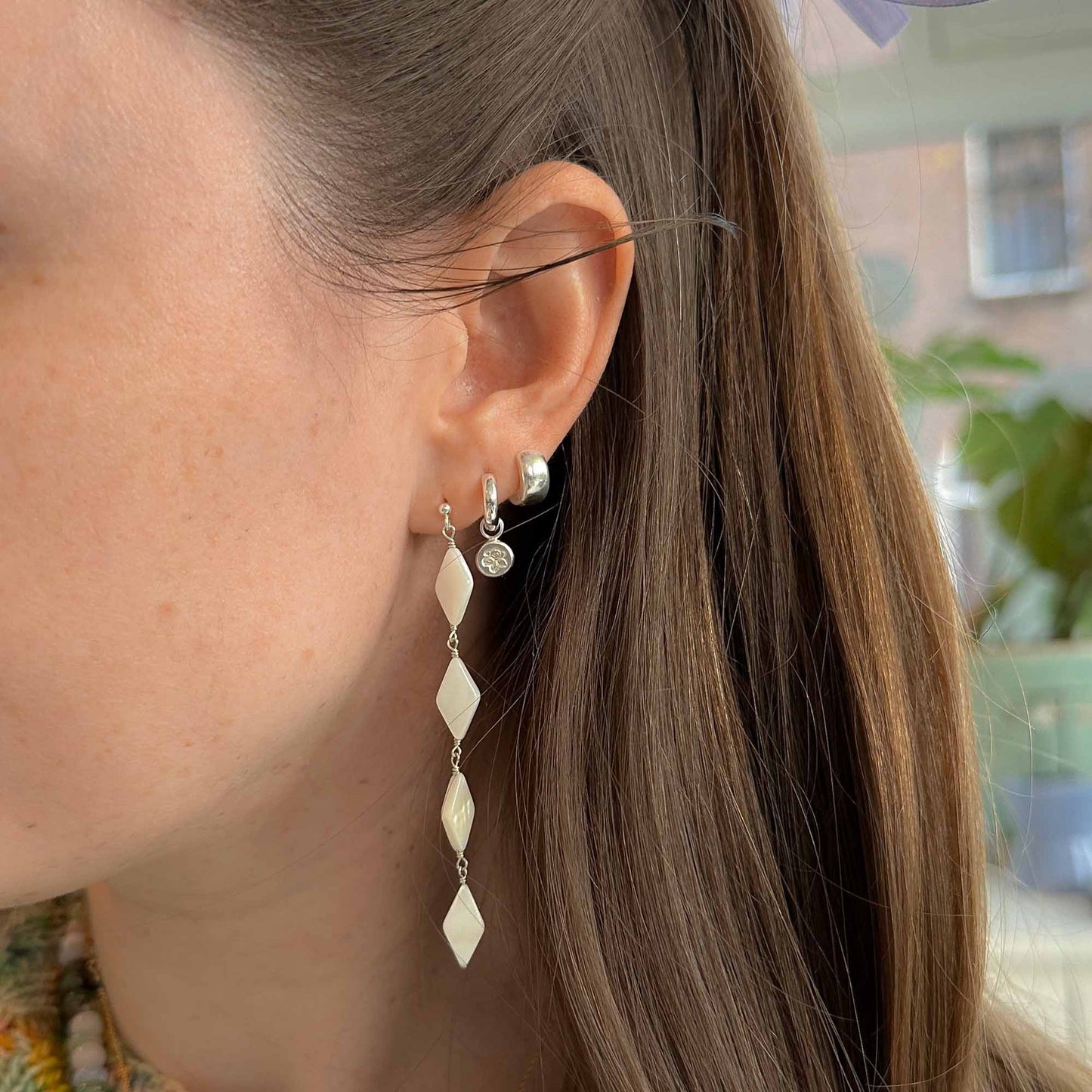 Close-up of a person wearing silver earrings with a blurred background