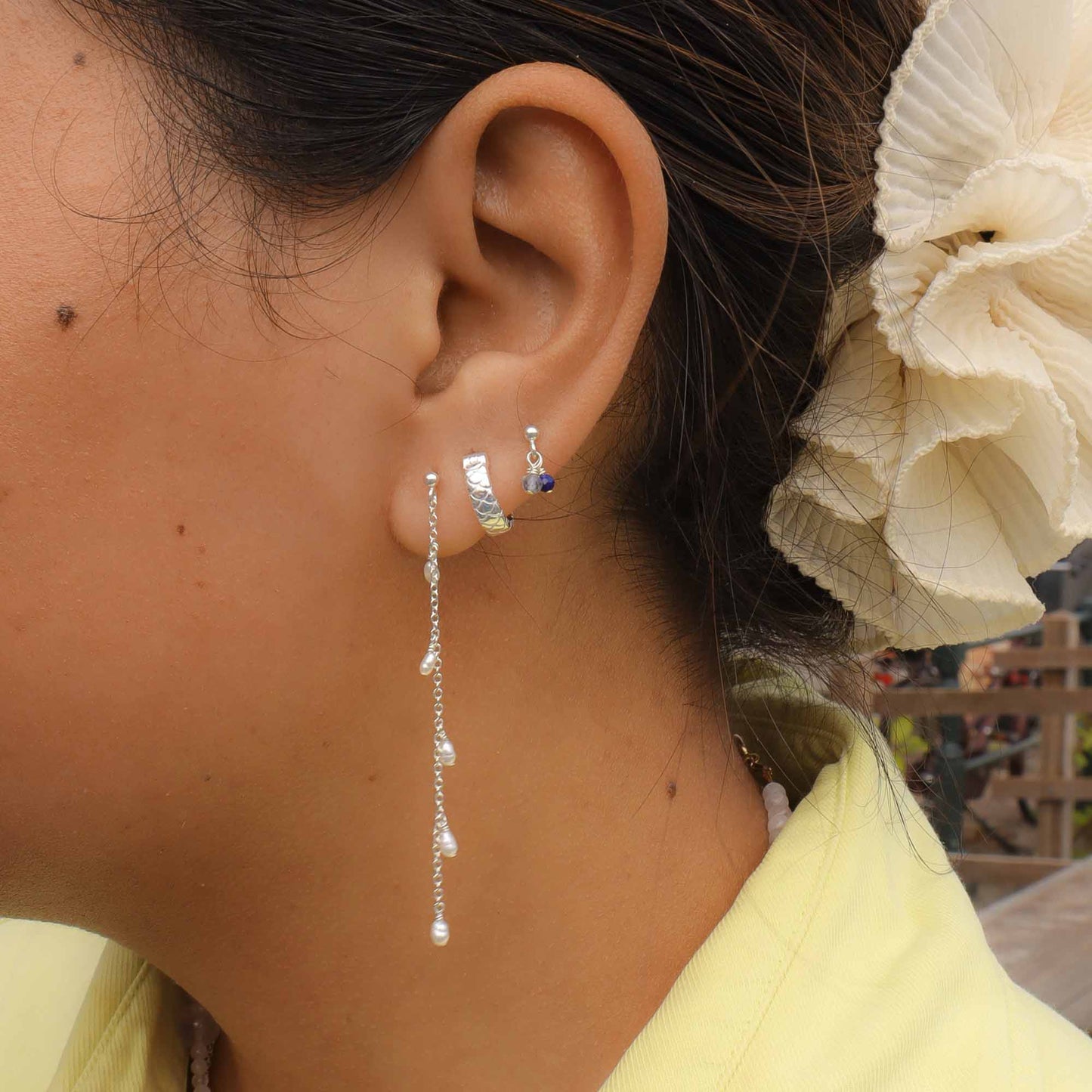 Close-up of a person wearing silver earrings with a blurred background