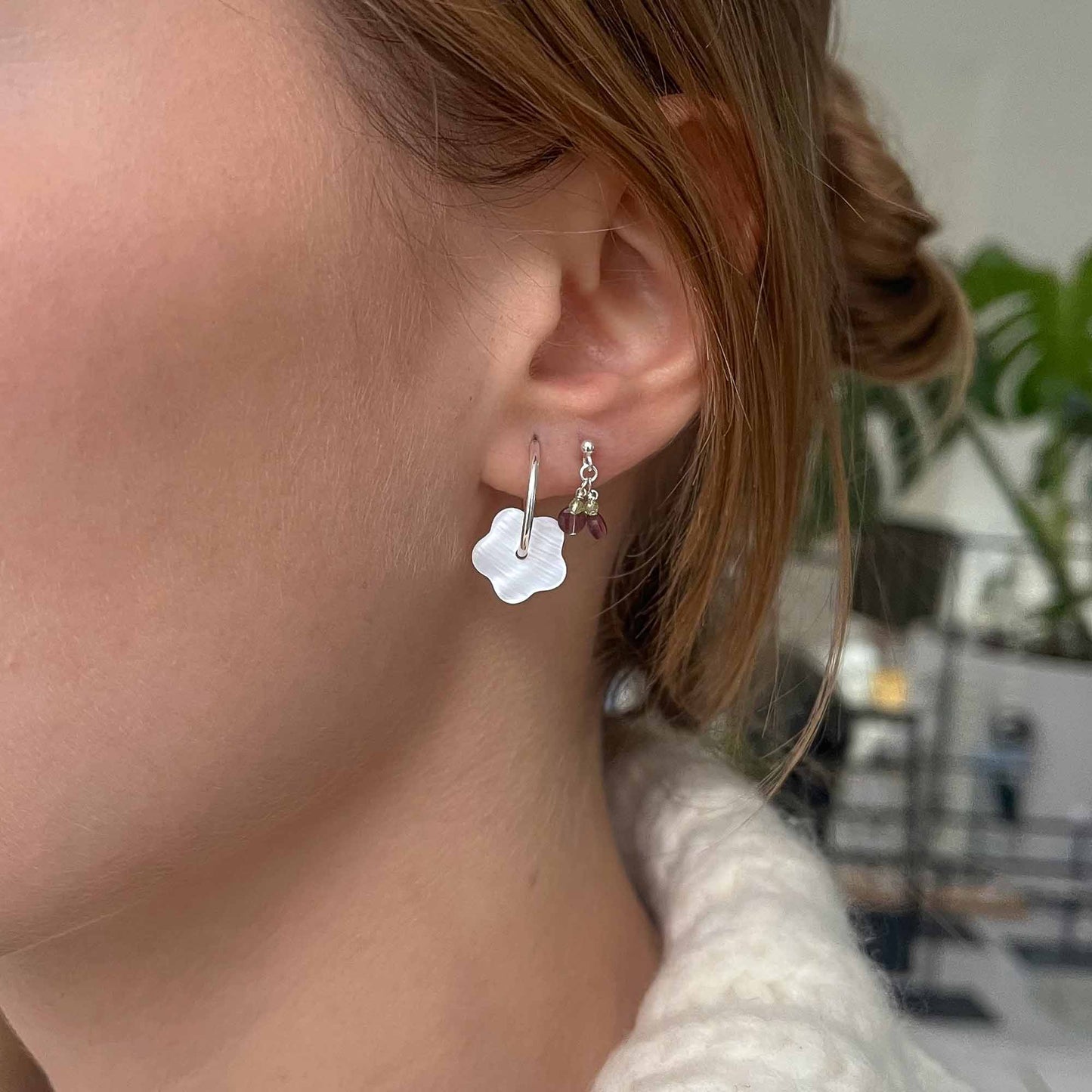 Close-up of a person wearing a silver earring with a flower design.