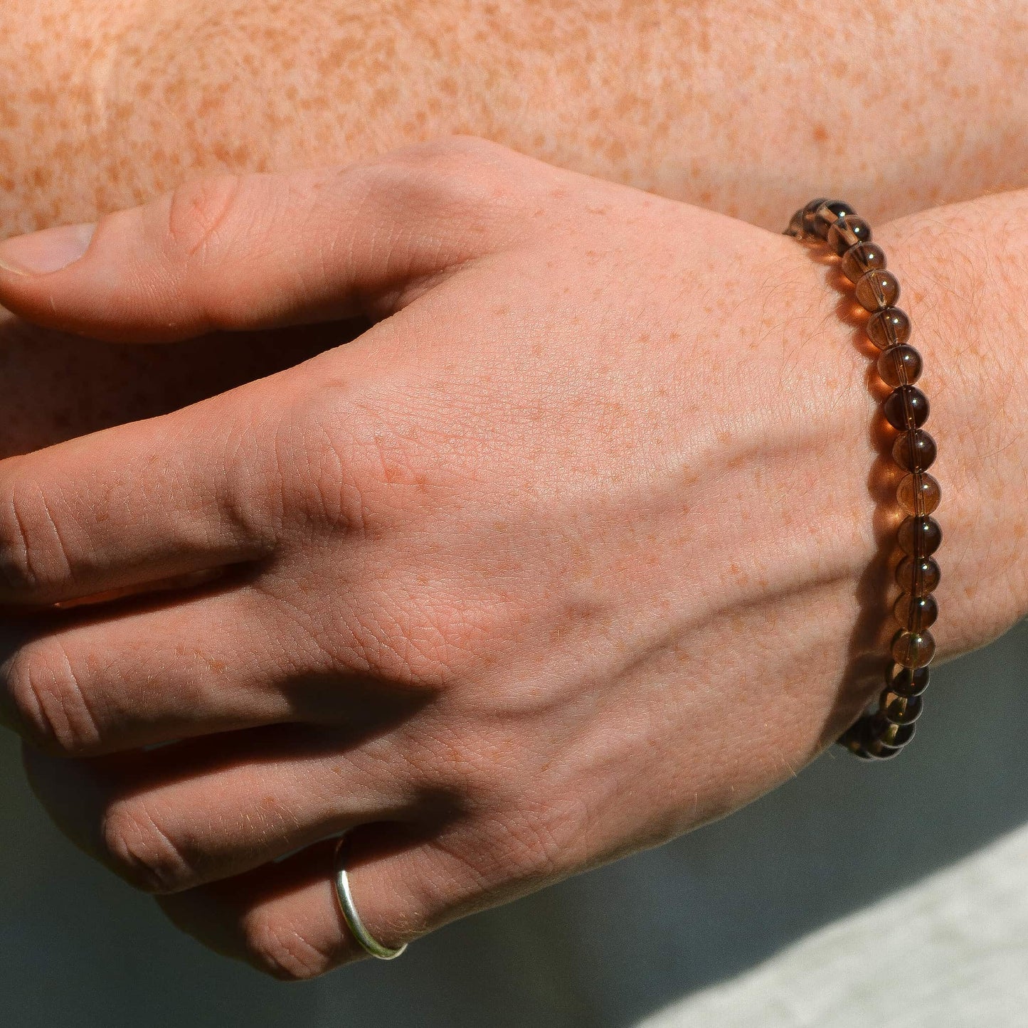 Hand wearing a beaded bracelet on a neutral background